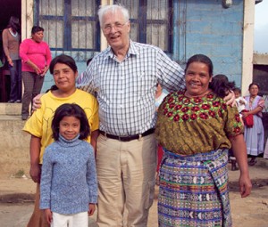 Wayne Hess posing with a mother and her children in front of the La Pedrera School